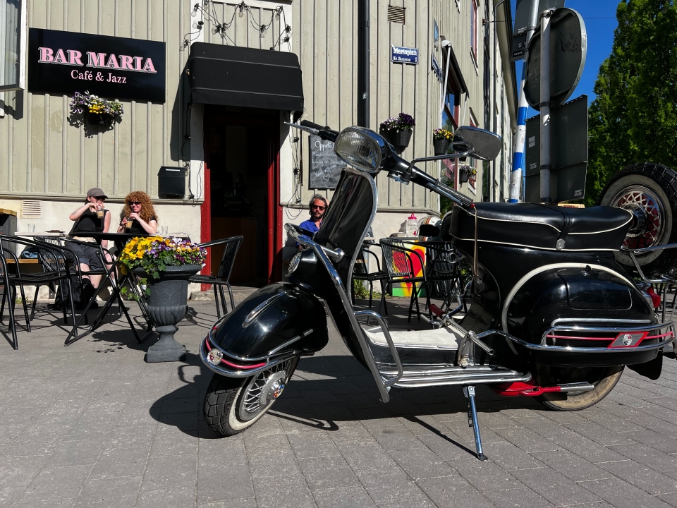 Svart Vespa parkerad utanför caféet.